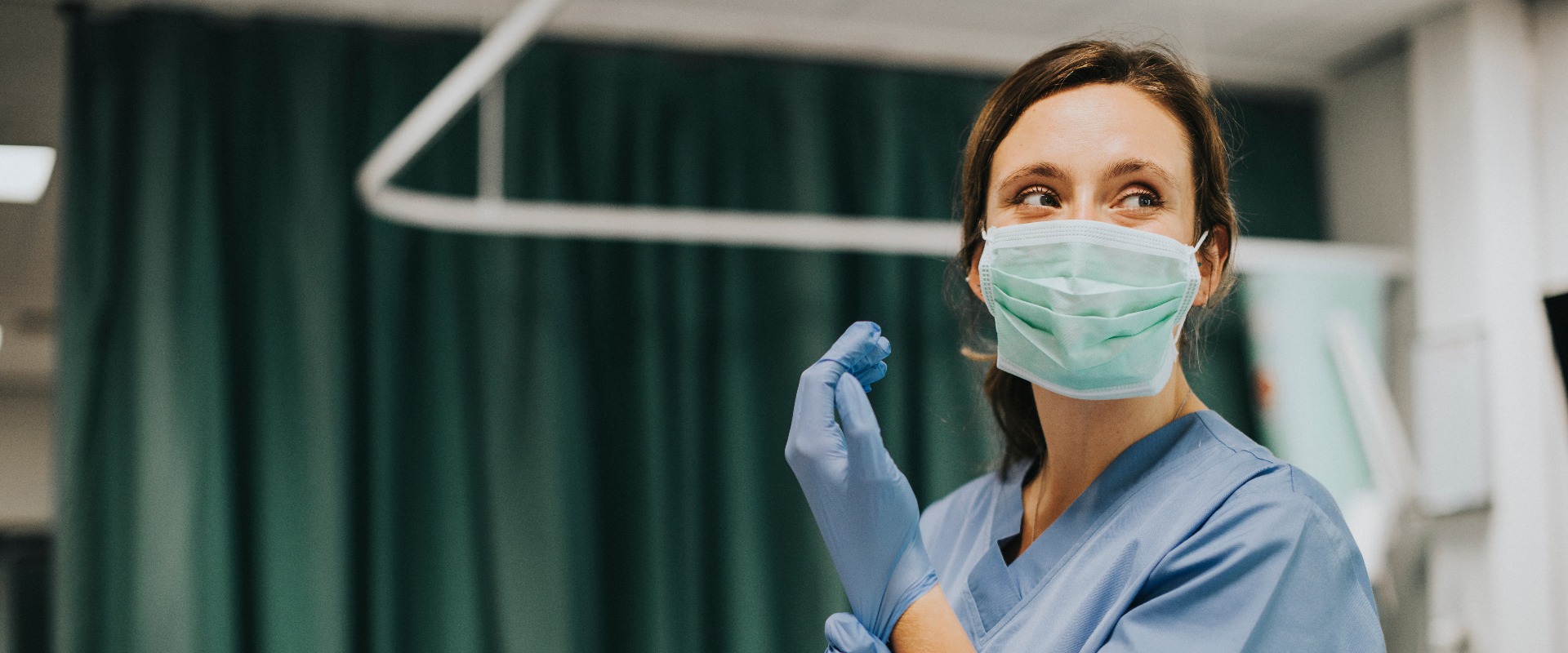 Nurse putting on gloves in hospital room